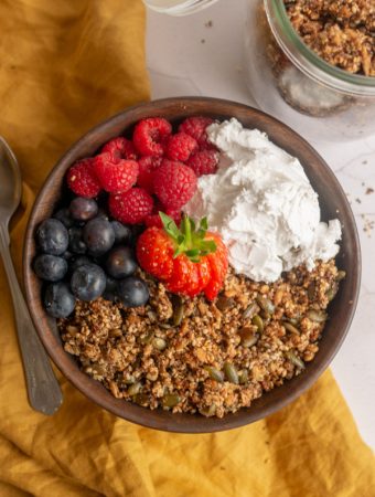 quinoa seed granola in a bowl with berries and yoghurt and a spoon